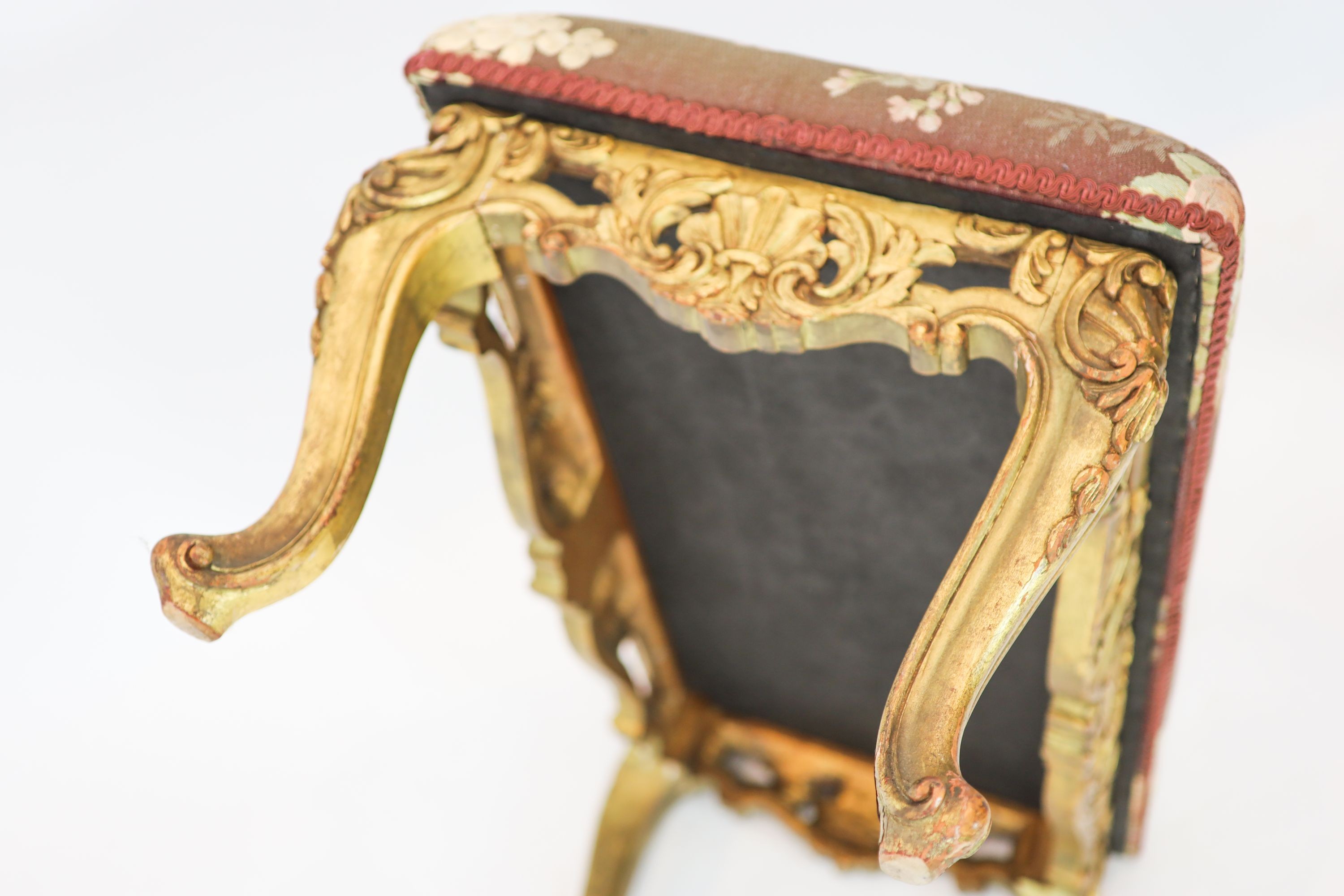 A Louis XV style carved giltwood dressing stool, with a pierced apron, on short cabriole legs, length 84cm, width 45cm, height 42cm